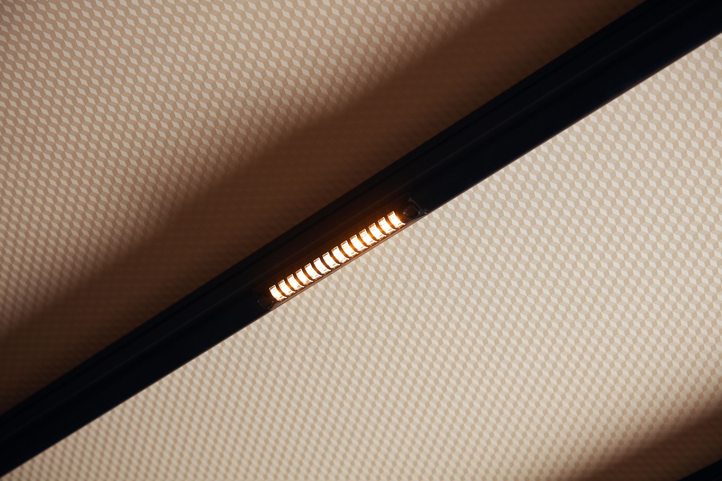 Warm brandende ledspot op een zwarte rail aan het plafond.