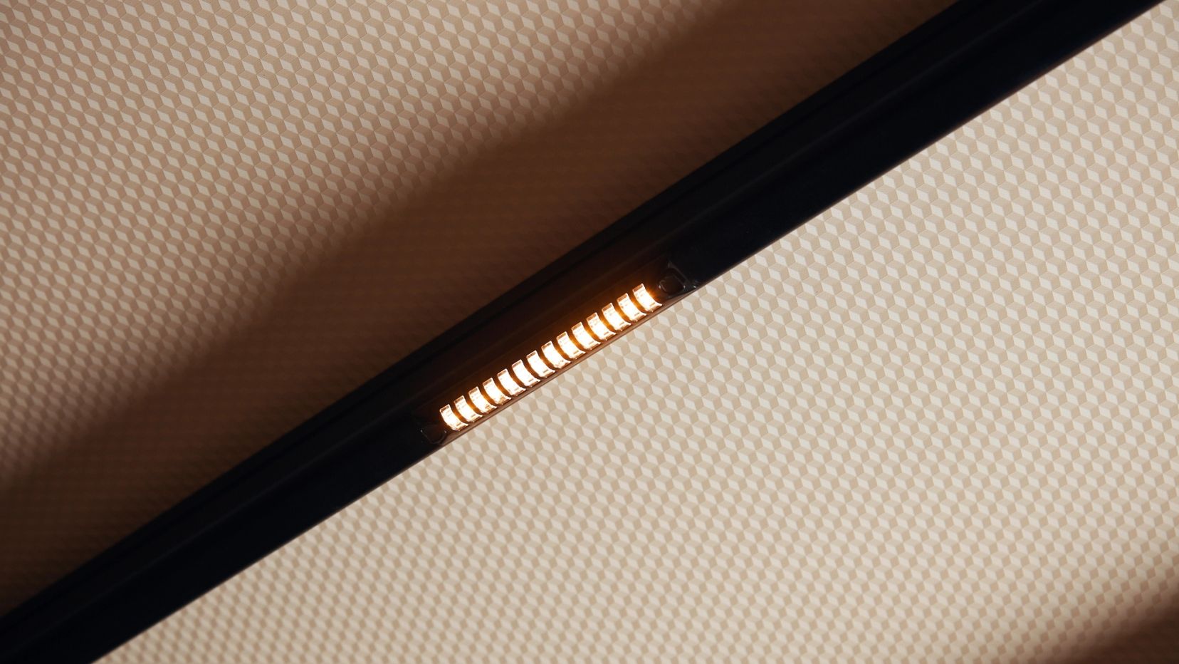 Warm brandende ledspot op een zwarte rail aan het plafond.