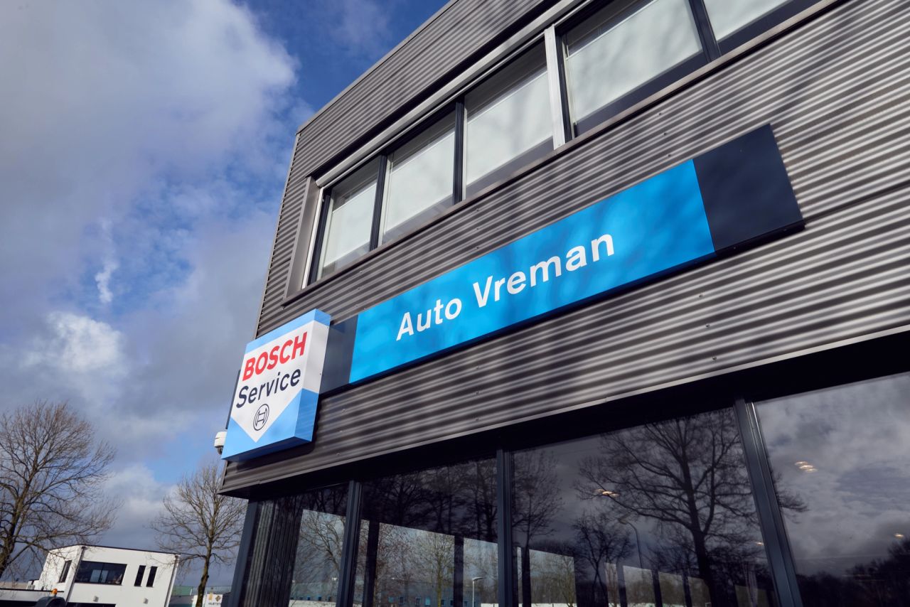 Gevel van het pand van Auto Vreman met Bosch Service-bord onder een blauwe lucht.
