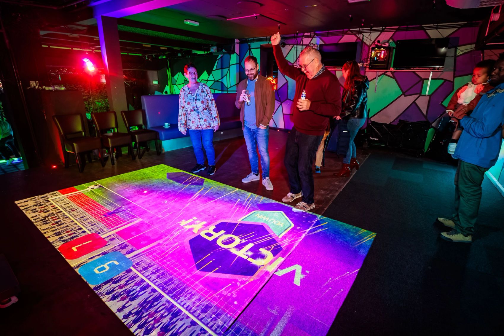 Gasten staan op een vloer met een paarse Victory-projectie bij Timestamp Arnhem, gemaakt door Bold Productions