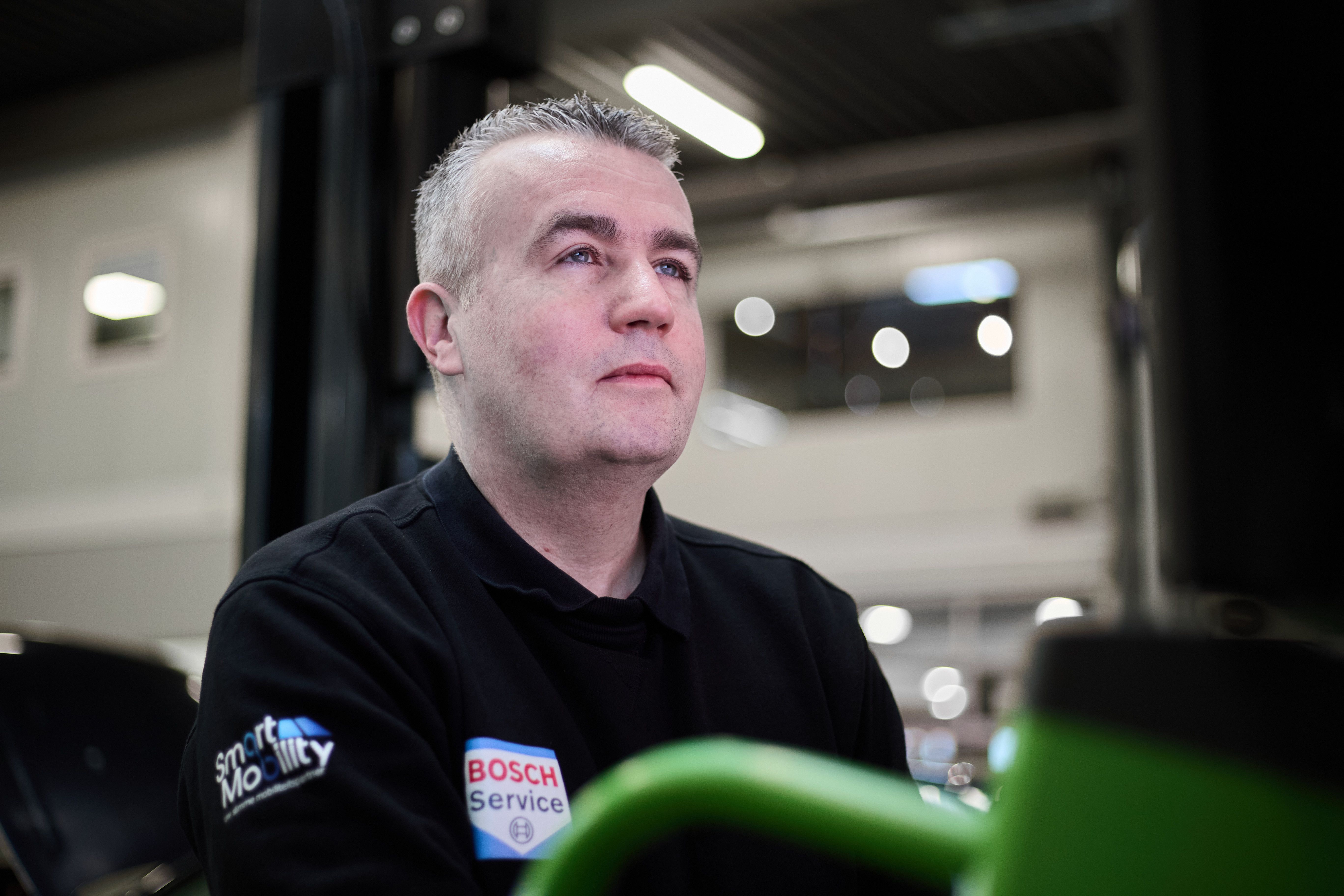 Portret van een monteur in zwarte werkkleding in de werkplaats van Auto Vreman.