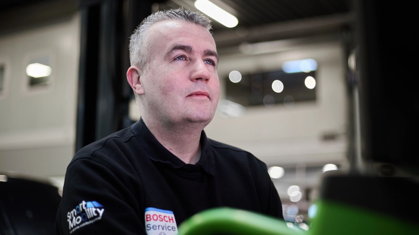 Portret van een monteur in zwarte werkkleding in de werkplaats van Auto Vreman.