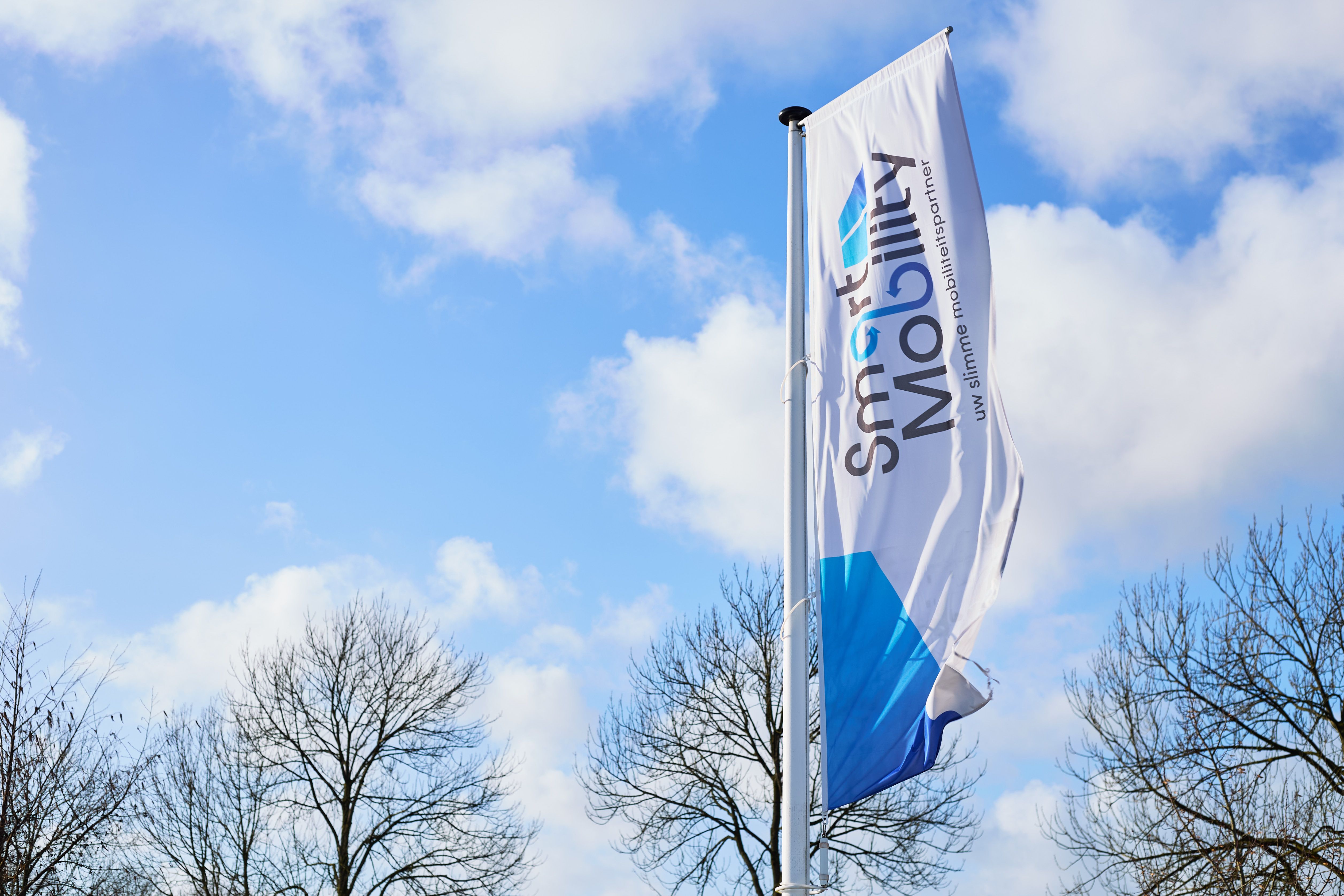 Vlag aan de vlaggenmast voor het pand van Auto Vreman onder een blauwe lucht, gemaakt door Bold Productions