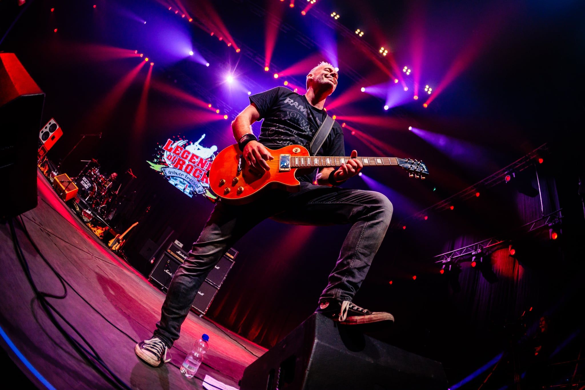 Gitarist met een rode gitaar op een podium in paars en rood licht, gemaakt door Bold Productions