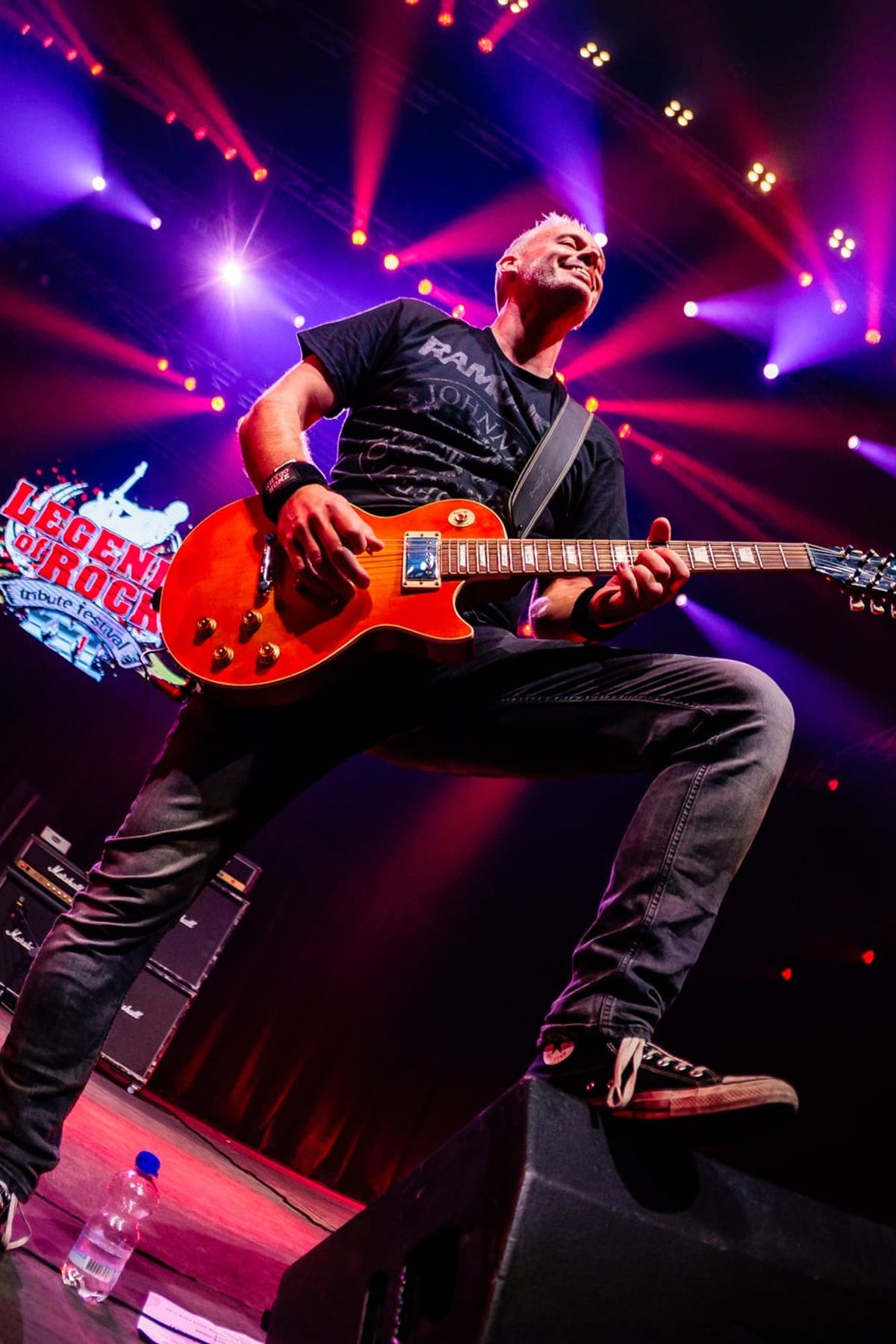 Gitarist met een rode gitaar op een podium in paars en rood licht, gemaakt door Bold Productions