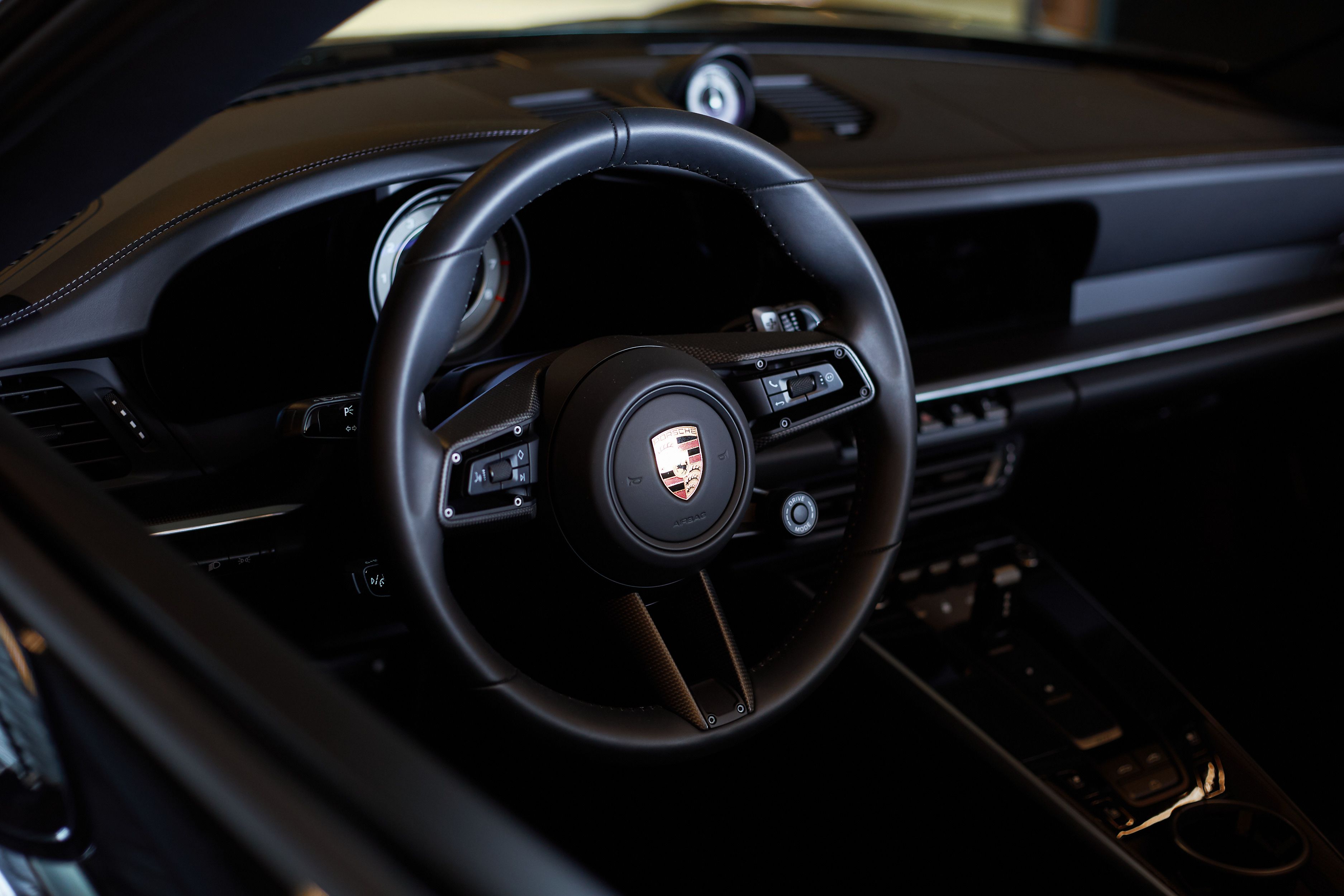 Close-up van het Porsche-stuur met Porsche-embleem.