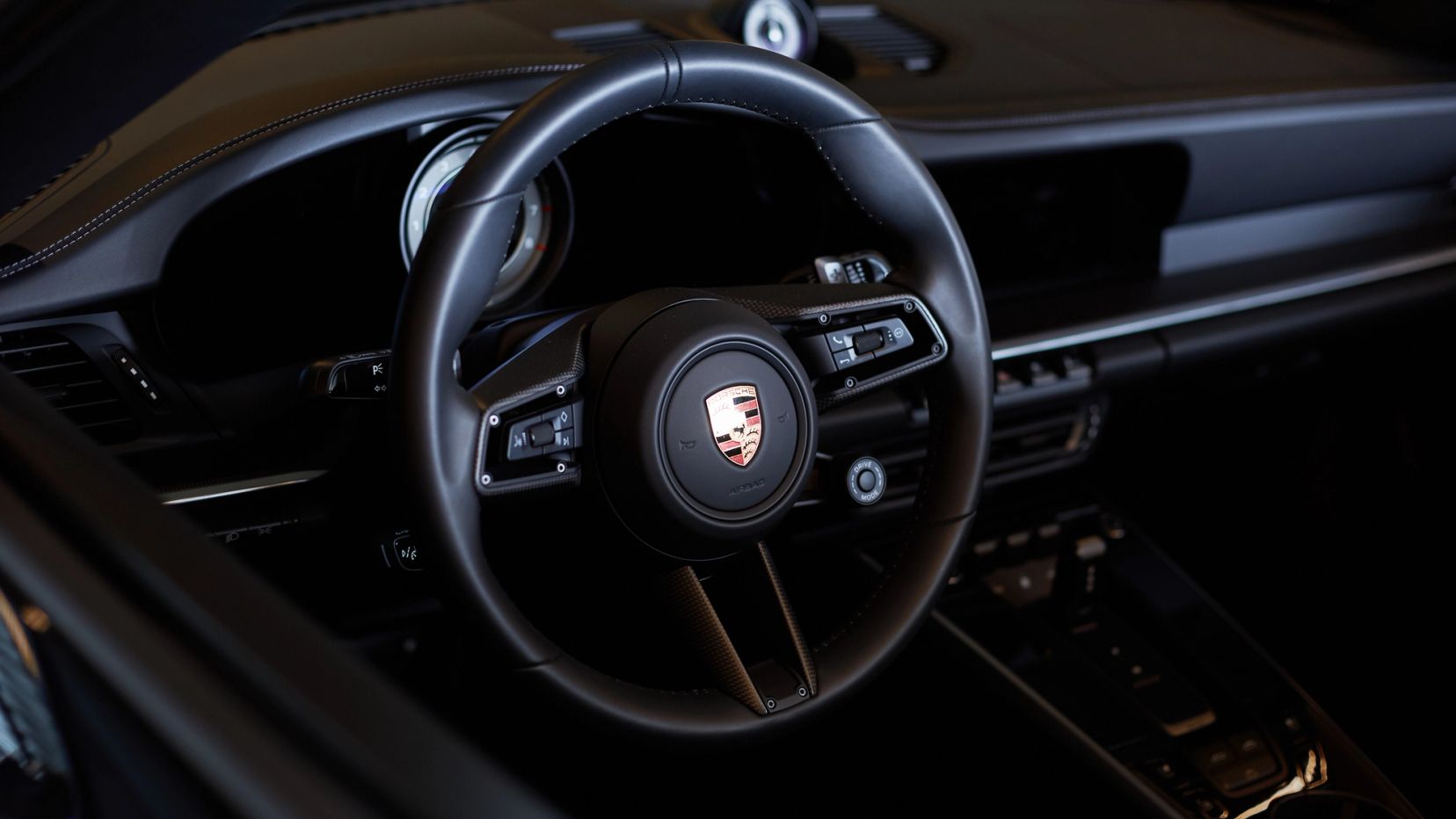Close-up van het Porsche-stuur met Porsche-embleem.