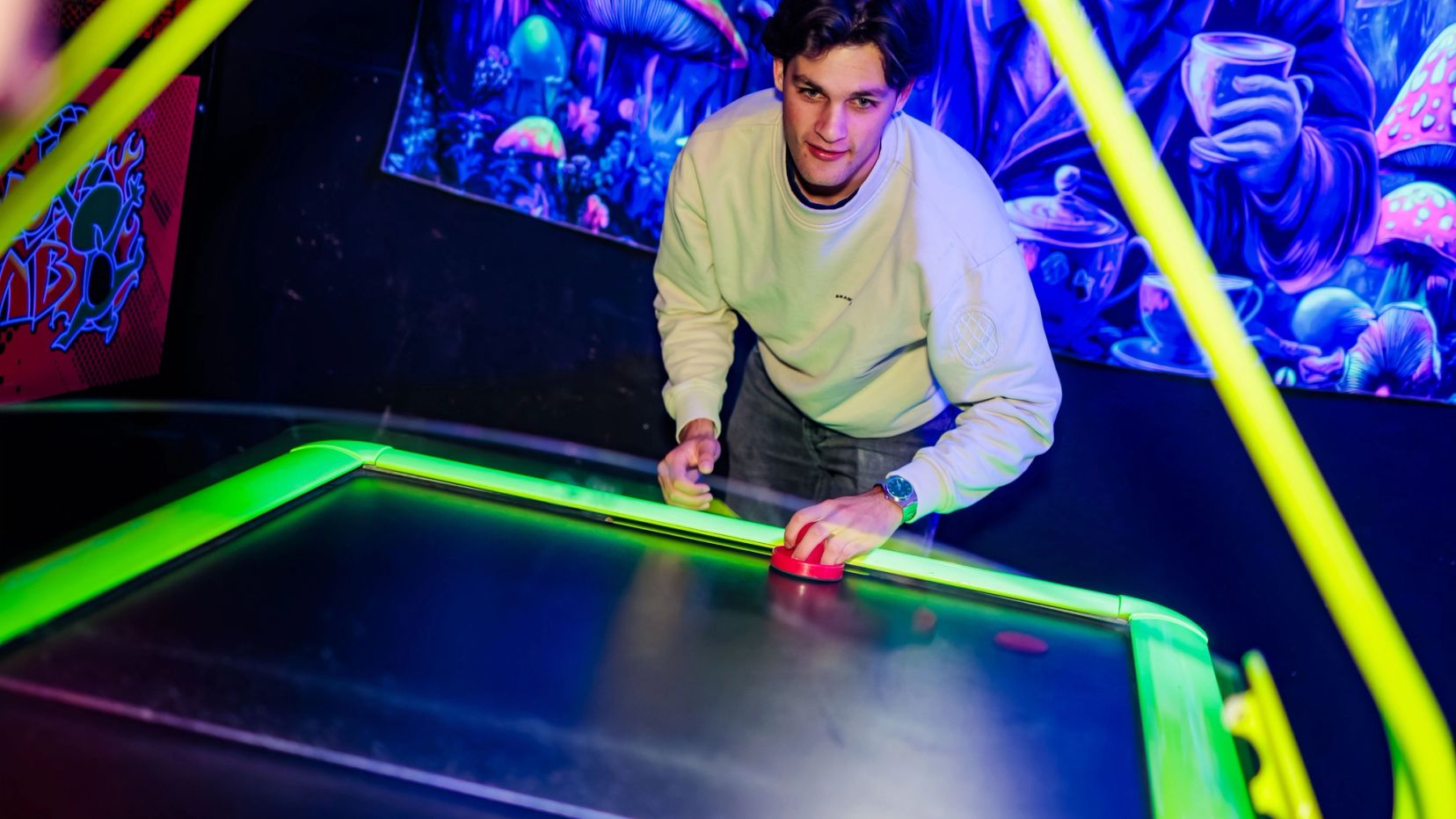 Man in lichte trui speelt airhockey bij Timestamp Arnhem.