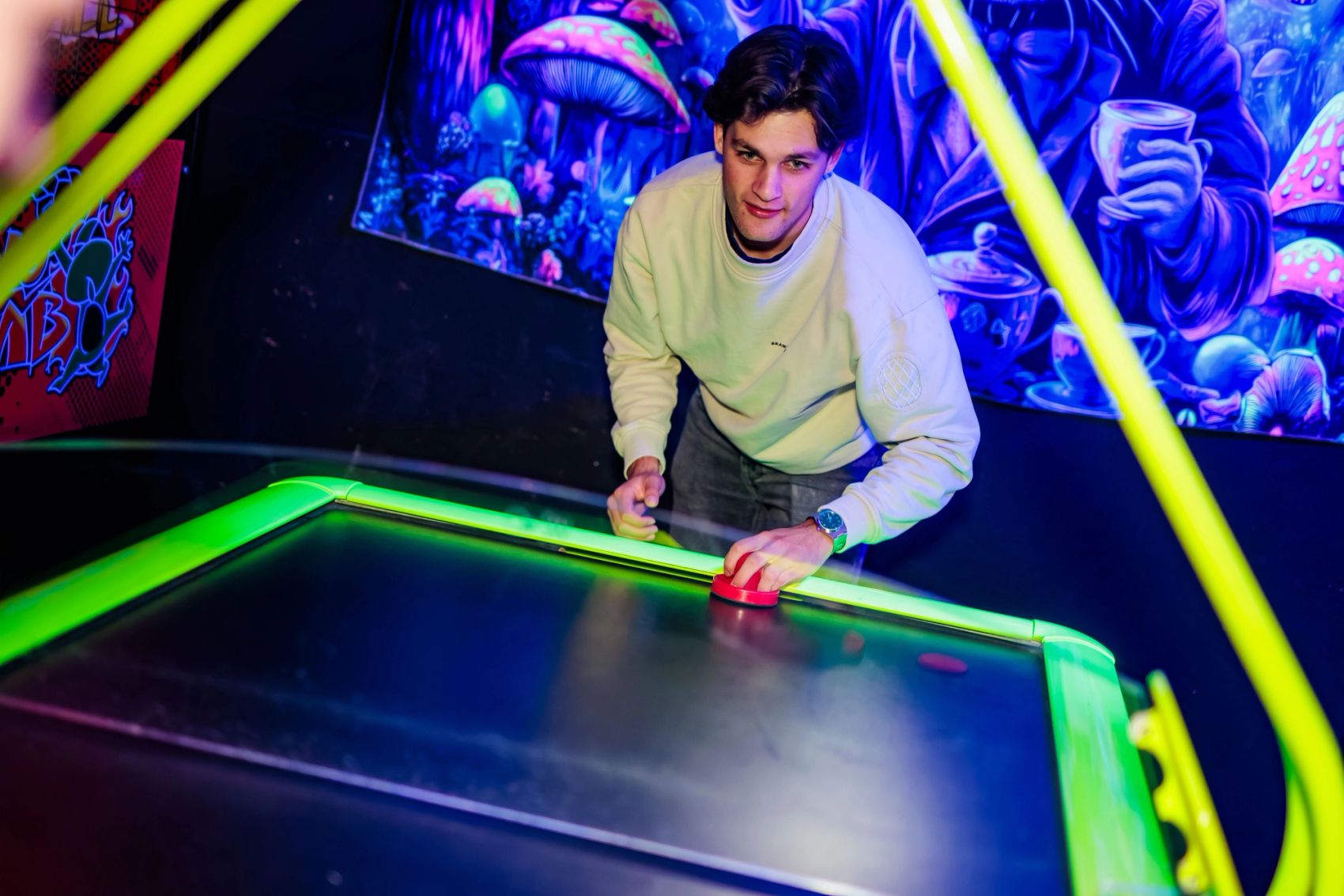 Man in lichte trui speelt airhockey voor een kleurrijke wand bij Timestamp Arnhem, gemaakt door Bold Productions