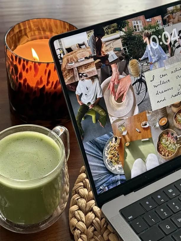 Ein Laptop mit einer persönlichen Fotosammlung neben einem grünen Getränk auf einem Cafétisch