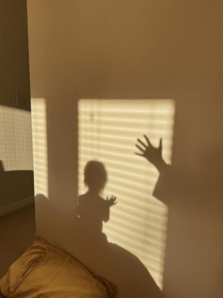 Die winkenden Schatten eines Elternteils und eines Kindes im warmen Licht