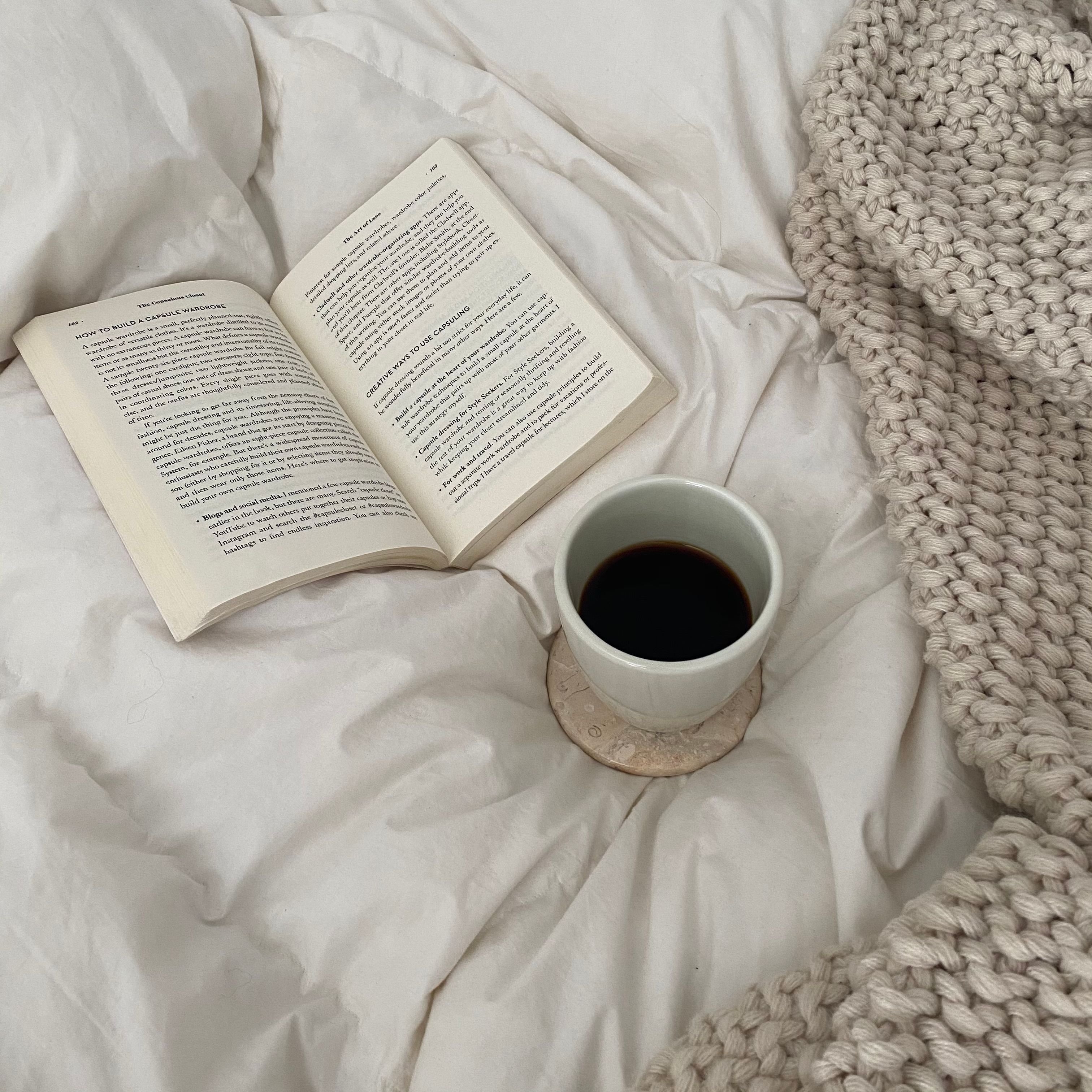 An open book and a cup of coffee on soft bedding