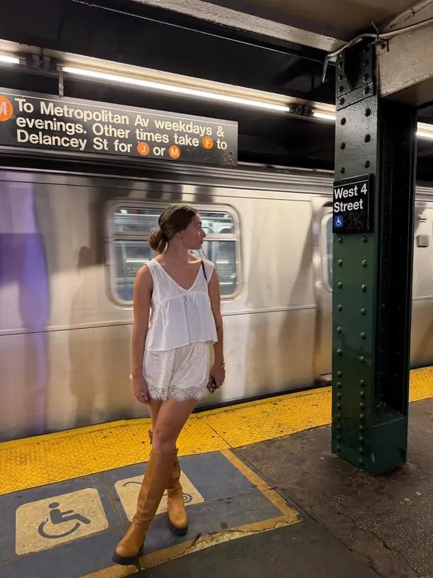 A woman waiting beside a moving train on a New York subway platform