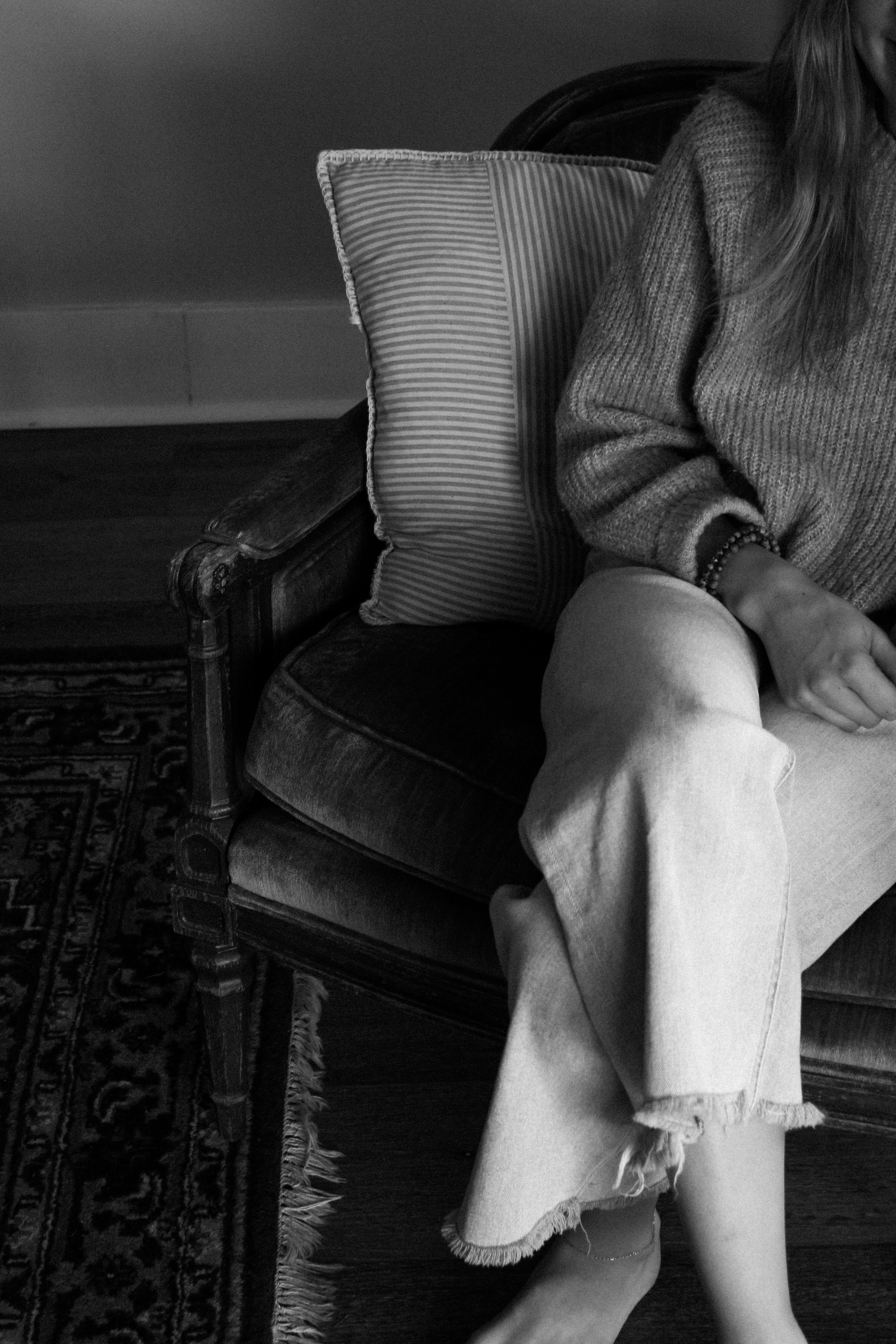 A quiet black-and-white portrait of a woman seated in a vintage armchair