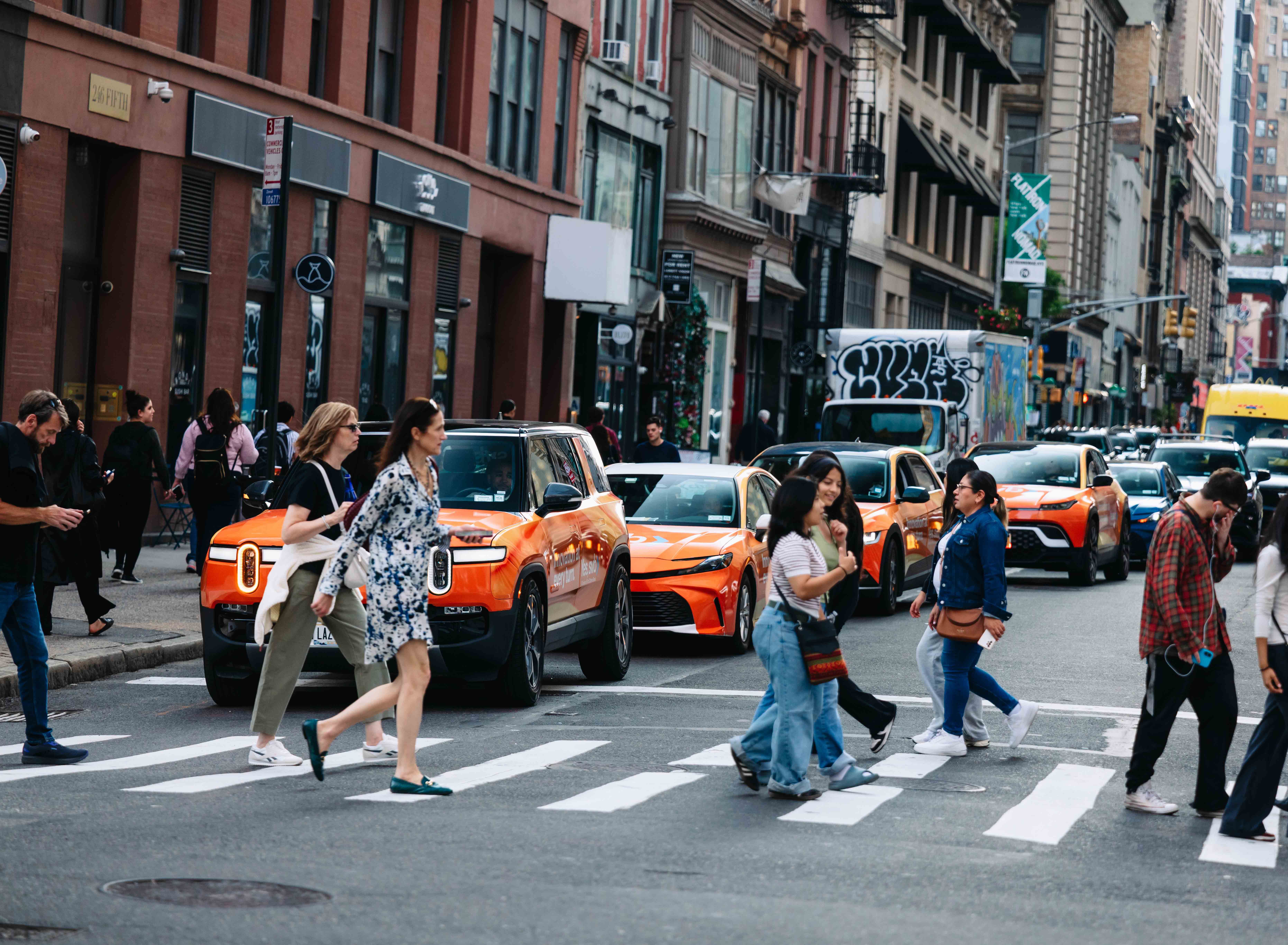 A fleet of wrapped rideshare vehicles driving down a city street