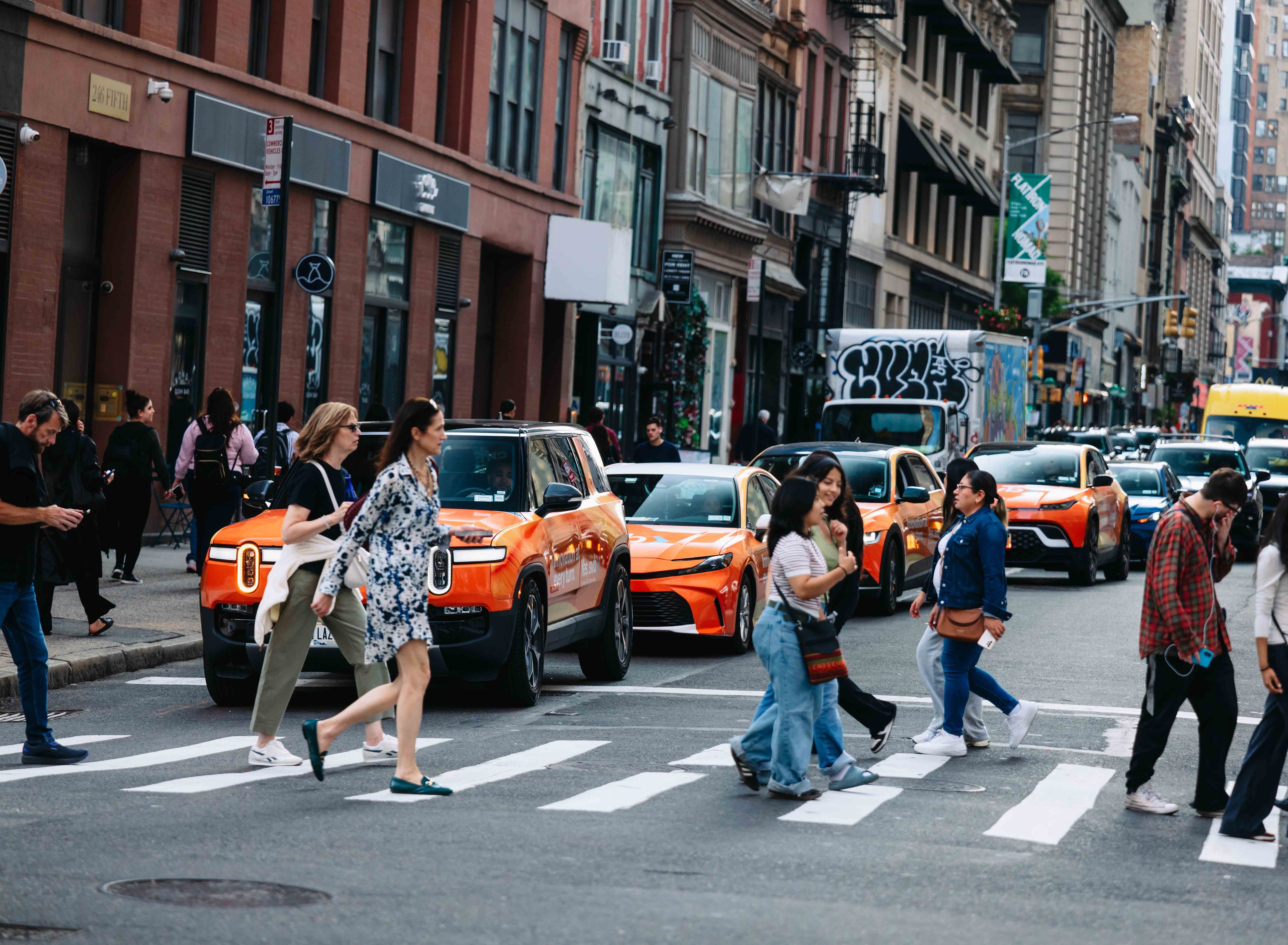 A fleet of wrapped rideshare vehicles driving down a city street