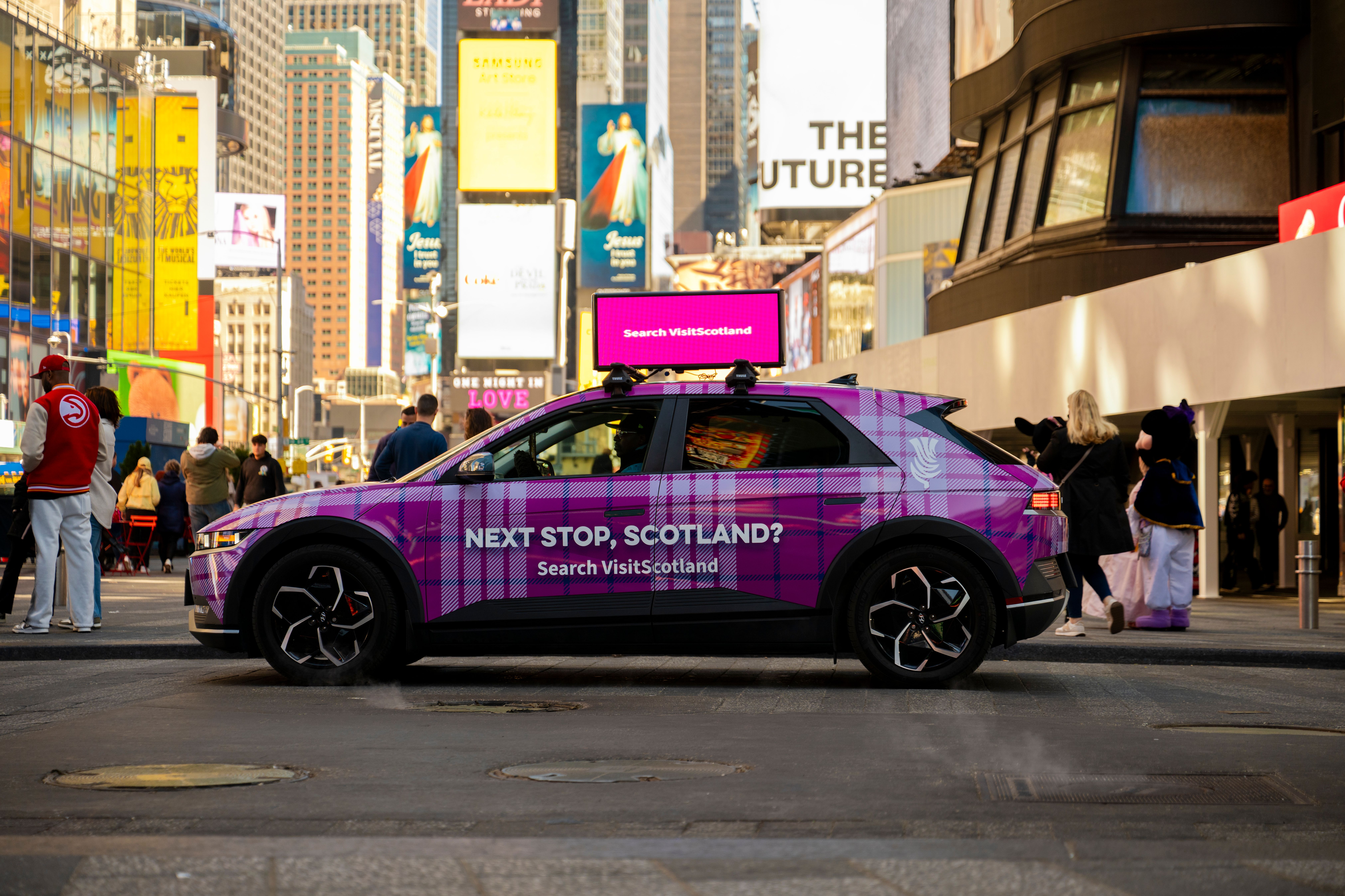 Tartan-wrapped car with wrap that reads "Next stop Scotland" with digital top