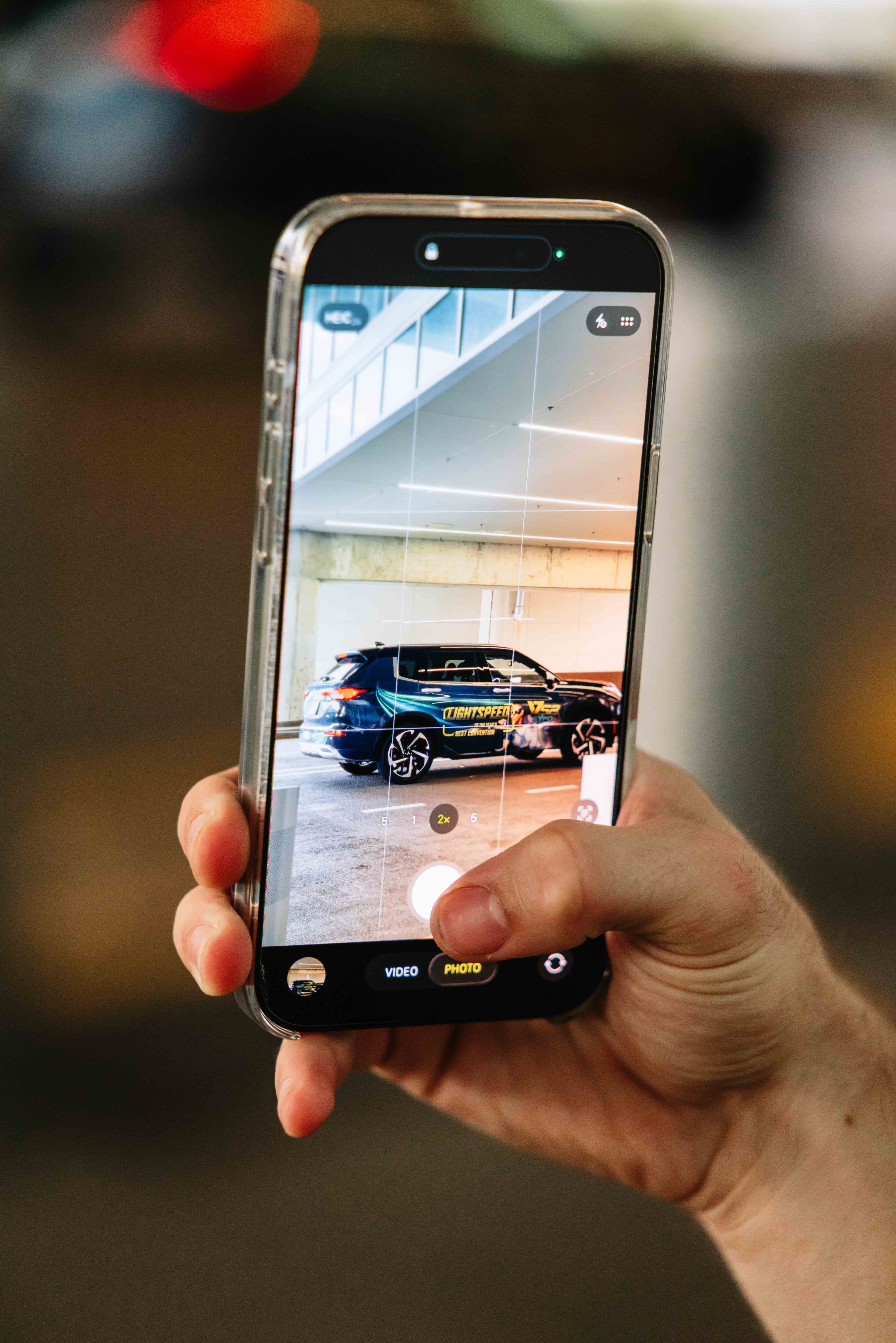 Man holding phone taking photo of wrapped car
