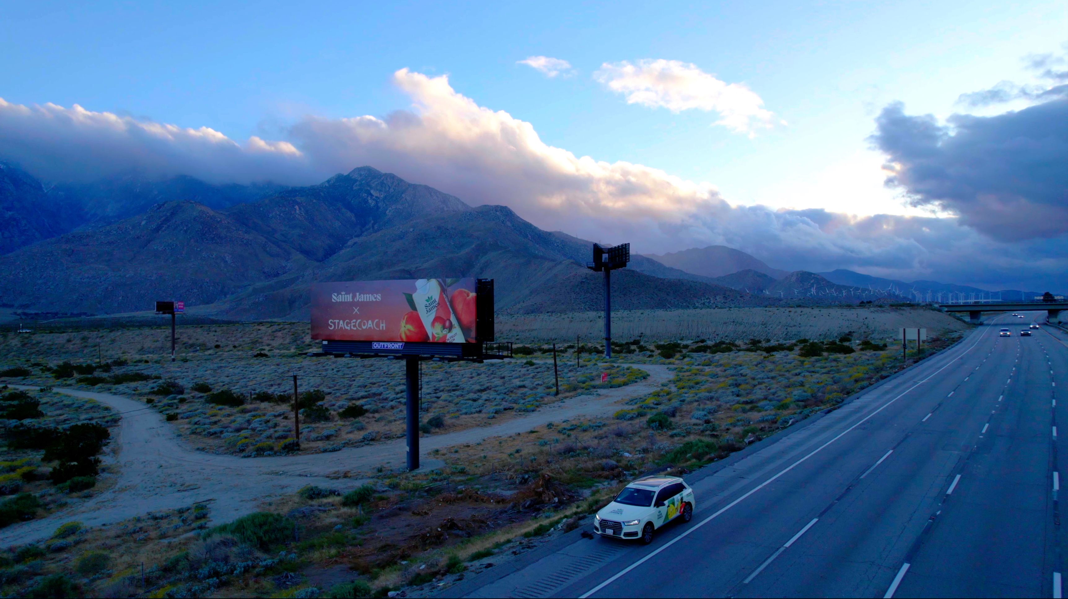 A car driving down a long road with a billboard off to the side