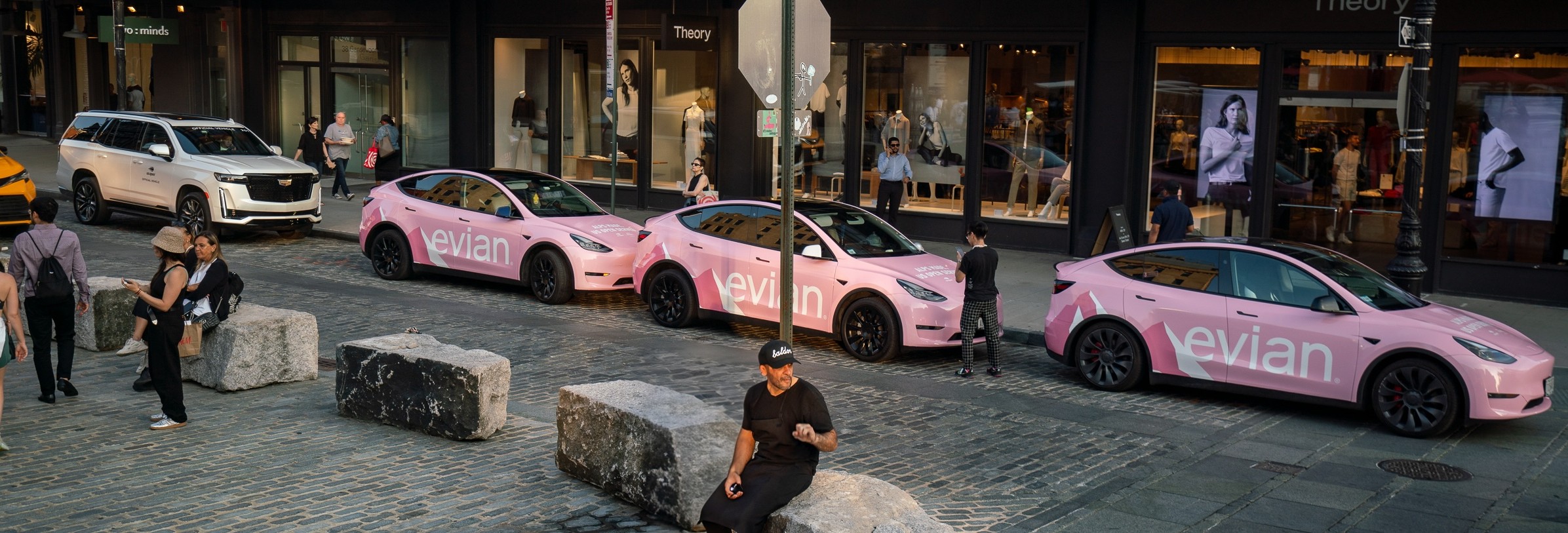 Evian-branded pink Tesla Model Y fleet parked on a cobblestone street