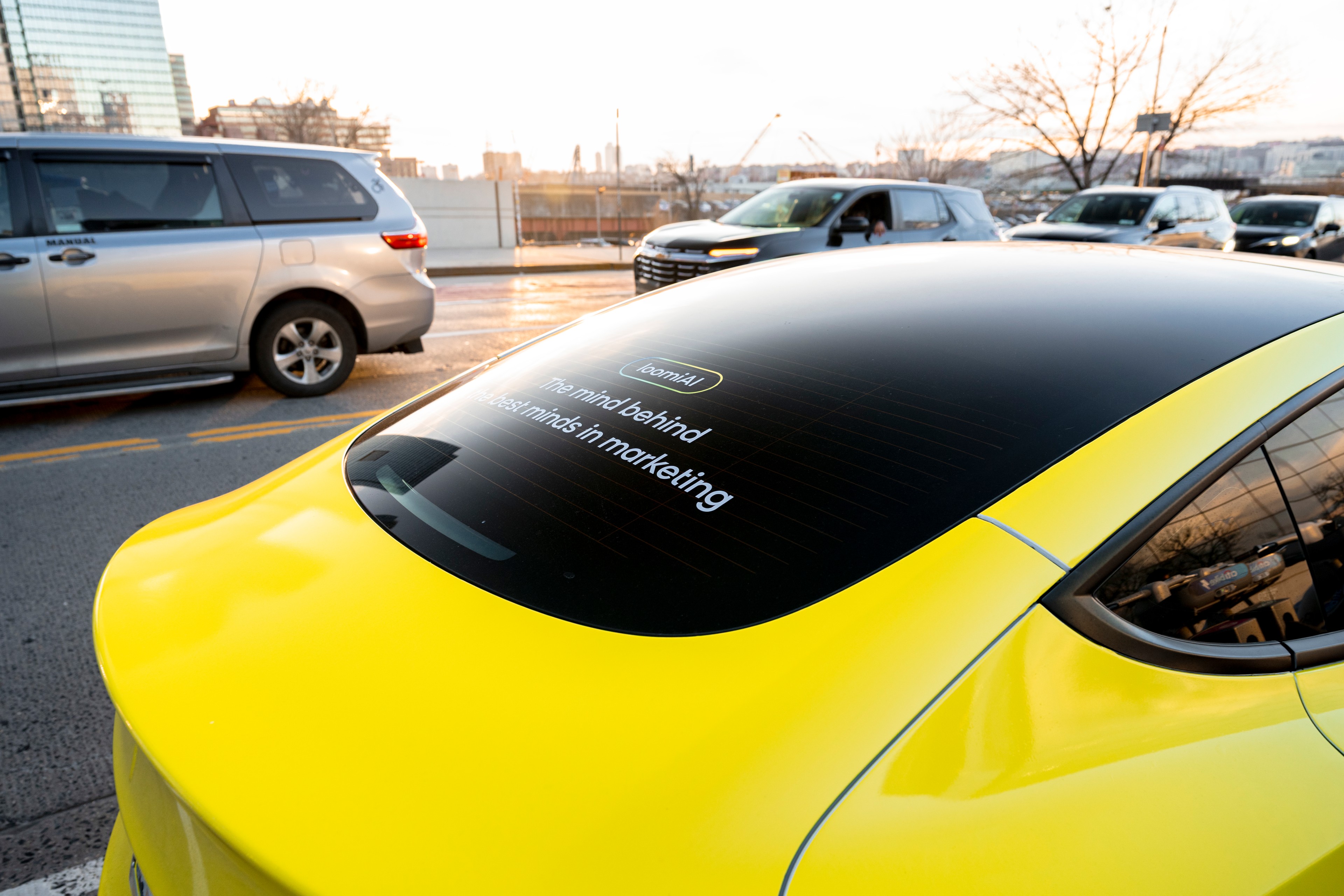 The rear windshield of a wrapped vehicle with a sticker reading "The mind behind the best minds in marketing" on it