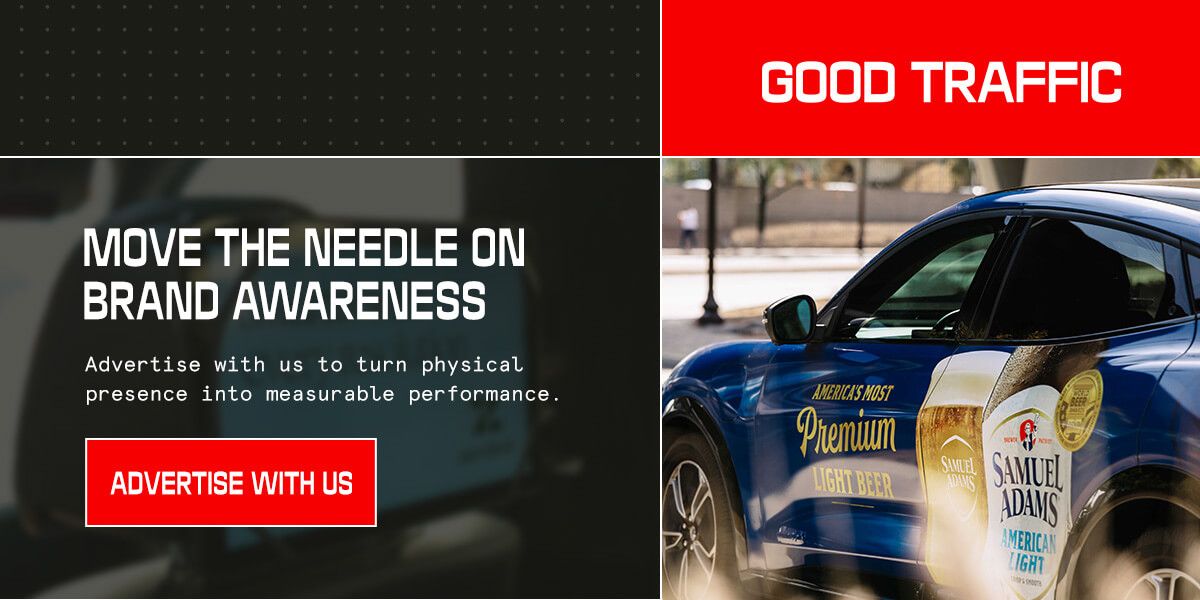 A Good Traffic promotional banner split into two panels. The left side features the headline "Move the Needle on Brand Awareness" with the subtext "Advertise with us to turn physical presence into measurable performance" and a red "Advertise With Us" CTA button. The right side shows a close-up photo of a blue car wrapped with Samuel Adams American Light beer branding, set against an outdoor urban backdrop.