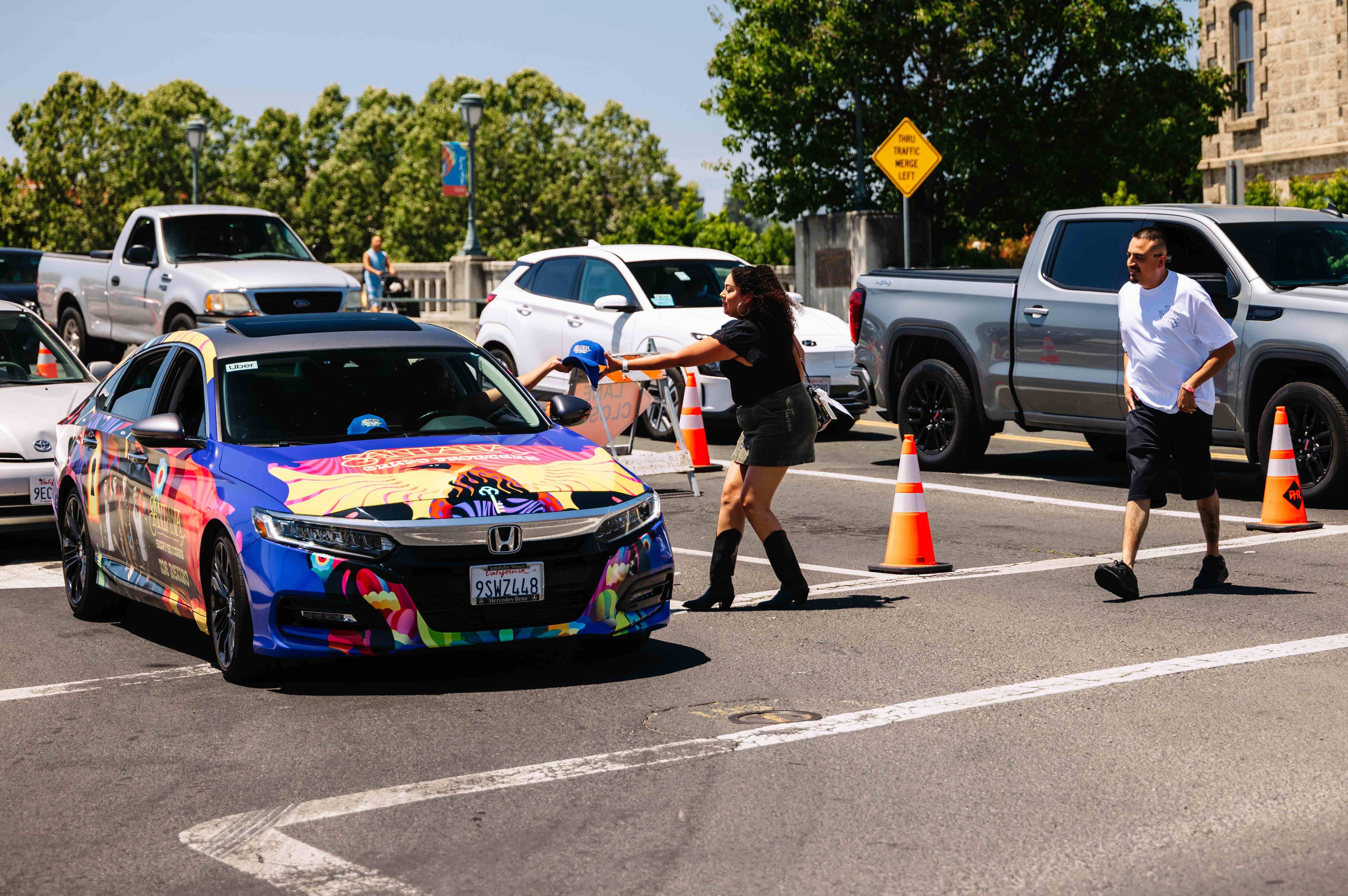 Brand ambassador handing out promotional merchandise from a colorfully wrapped Honda during a street-level marketing activation in California