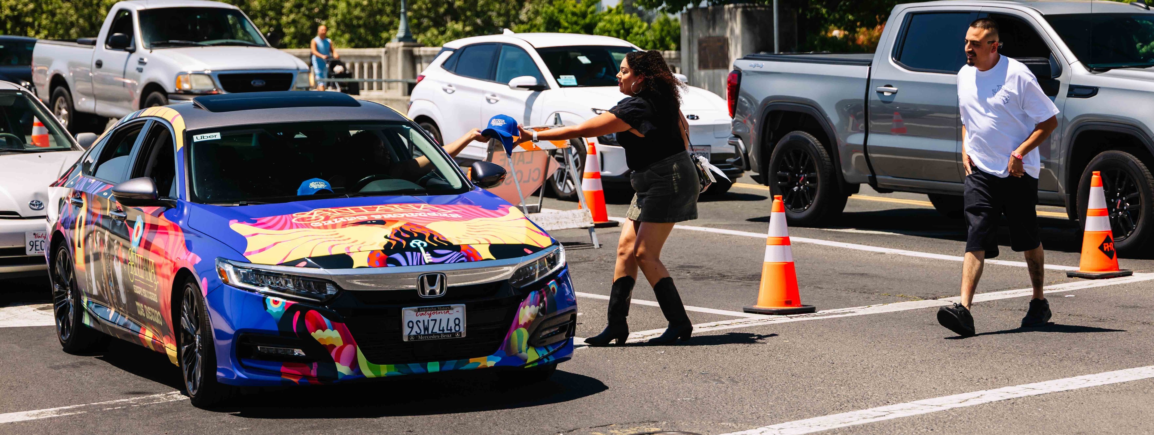 Brand ambassador handing out promotional merchandise from a colorfully wrapped Honda during a street-level marketing activation in California