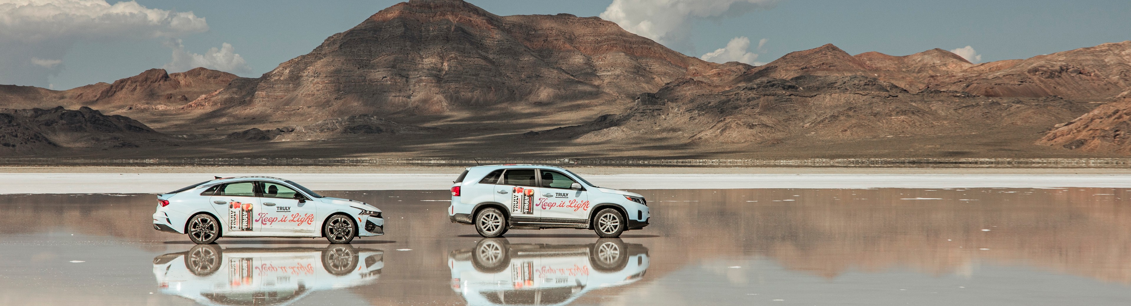 Truly Hard Seltzer 'Keep it Light' branded vehicles reflecting on the Bonneville Salt Flats in Utah with mountain backdrop