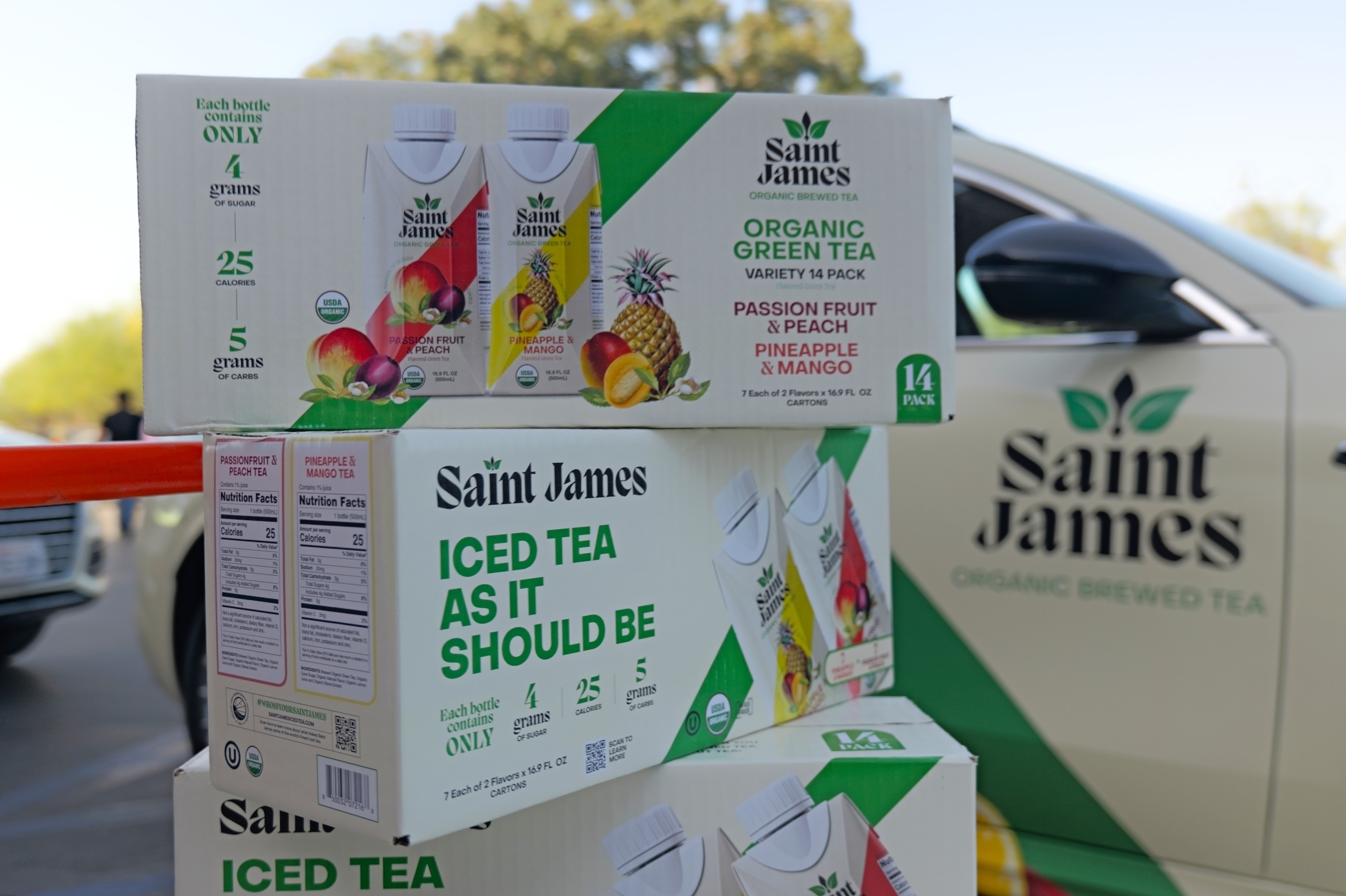 Saint James Organic Brewed Tea variety 14-pack boxes displayed in front of a branded vehicle during a product sampling activation.