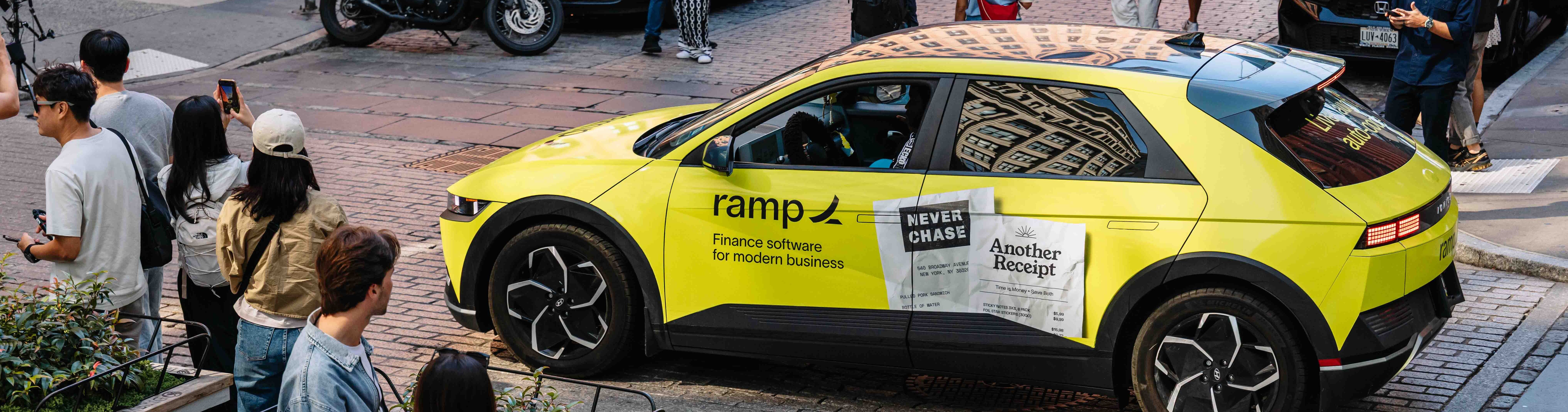 Ramp Finance neon yellow-wrapped Hyundai IONIQ 5 attracting pedestrians on a cobblestone street