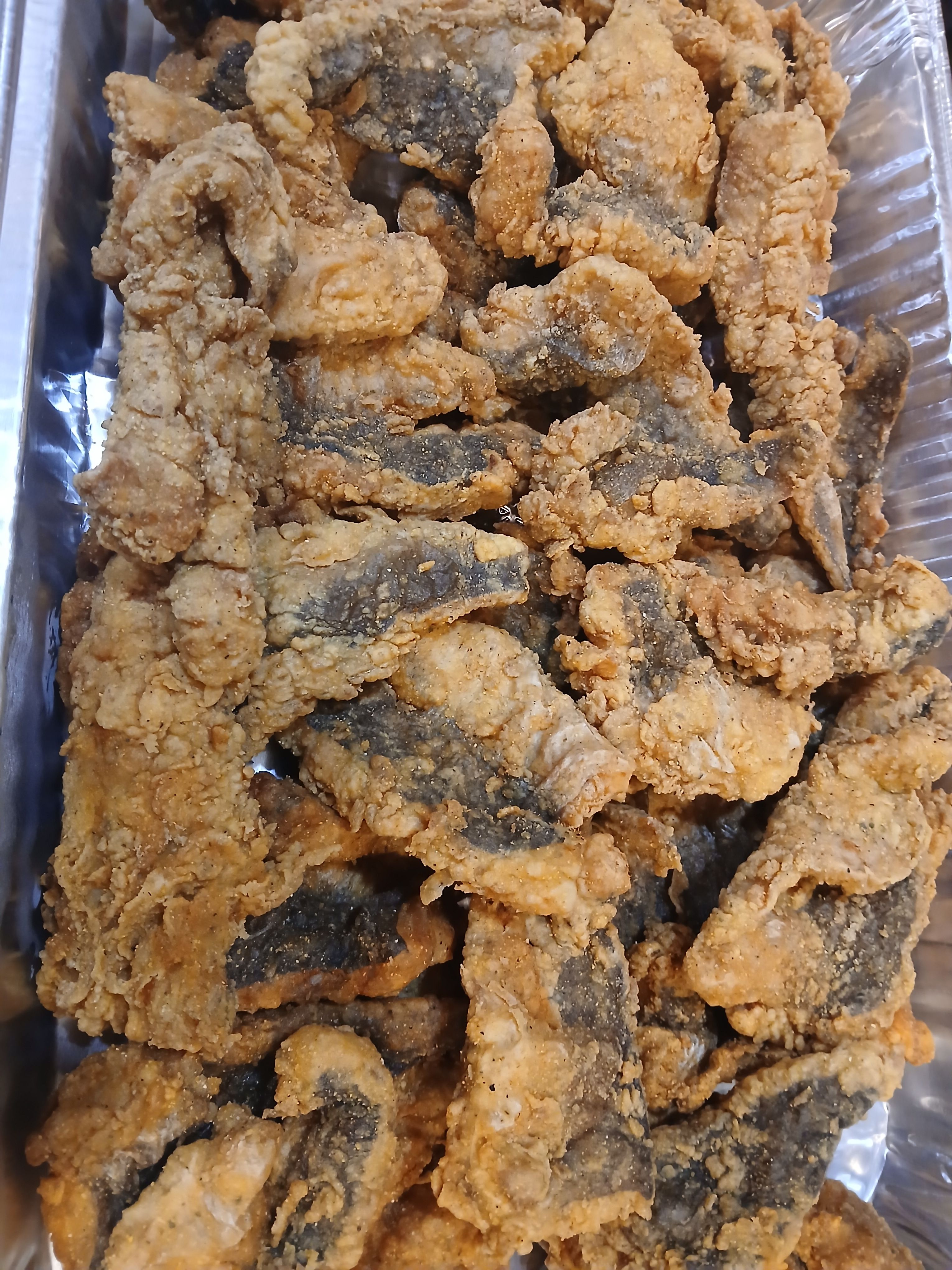 A large catering tray of golden-brown crispy fried fish pieces, perfect for events and parties in Flatbush, Brooklyn.