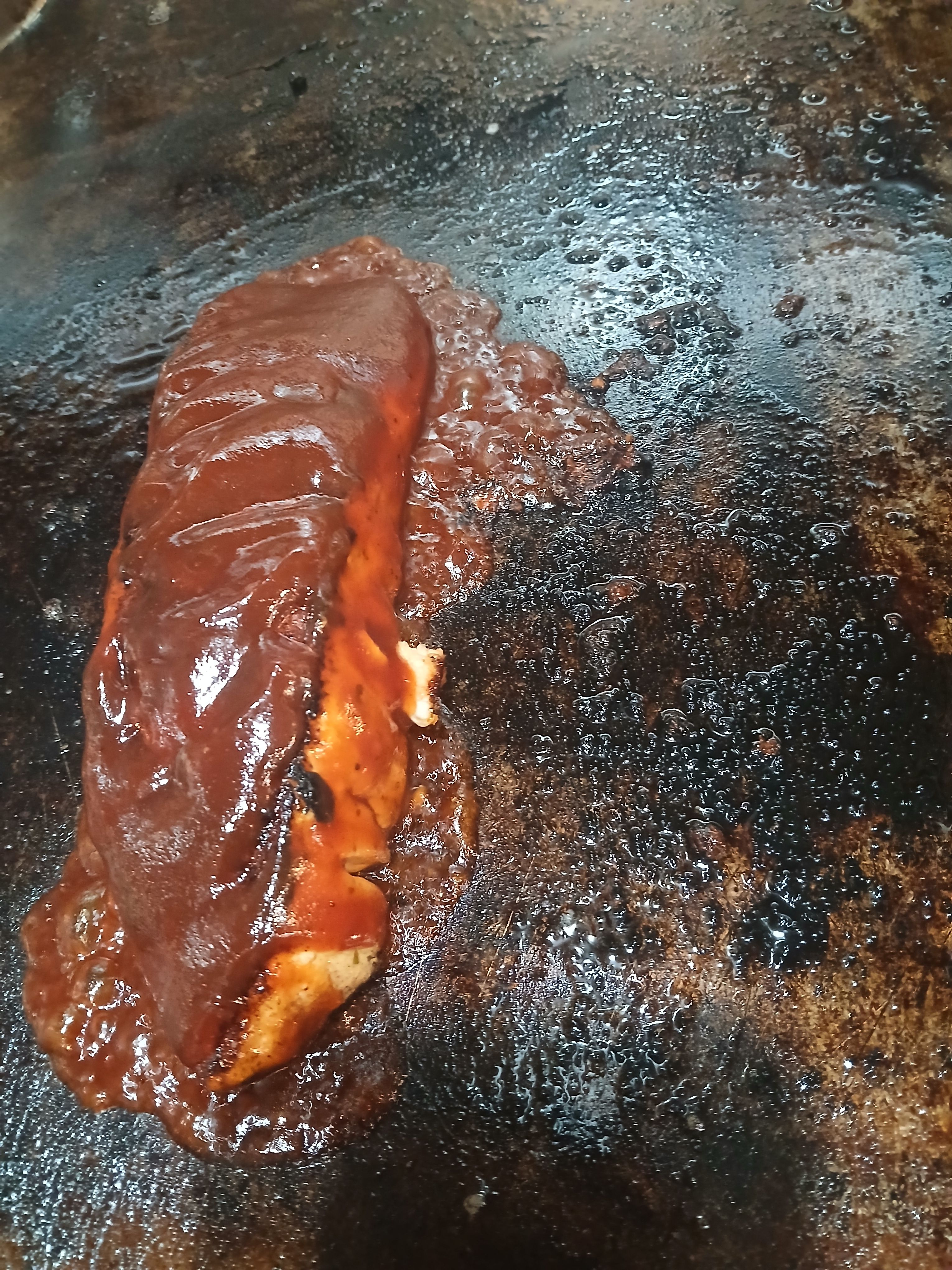 A sustainably sourced salmon fillet being grilled and smothered in a rich, flavorful house-made Caribbean barbecue sauce.