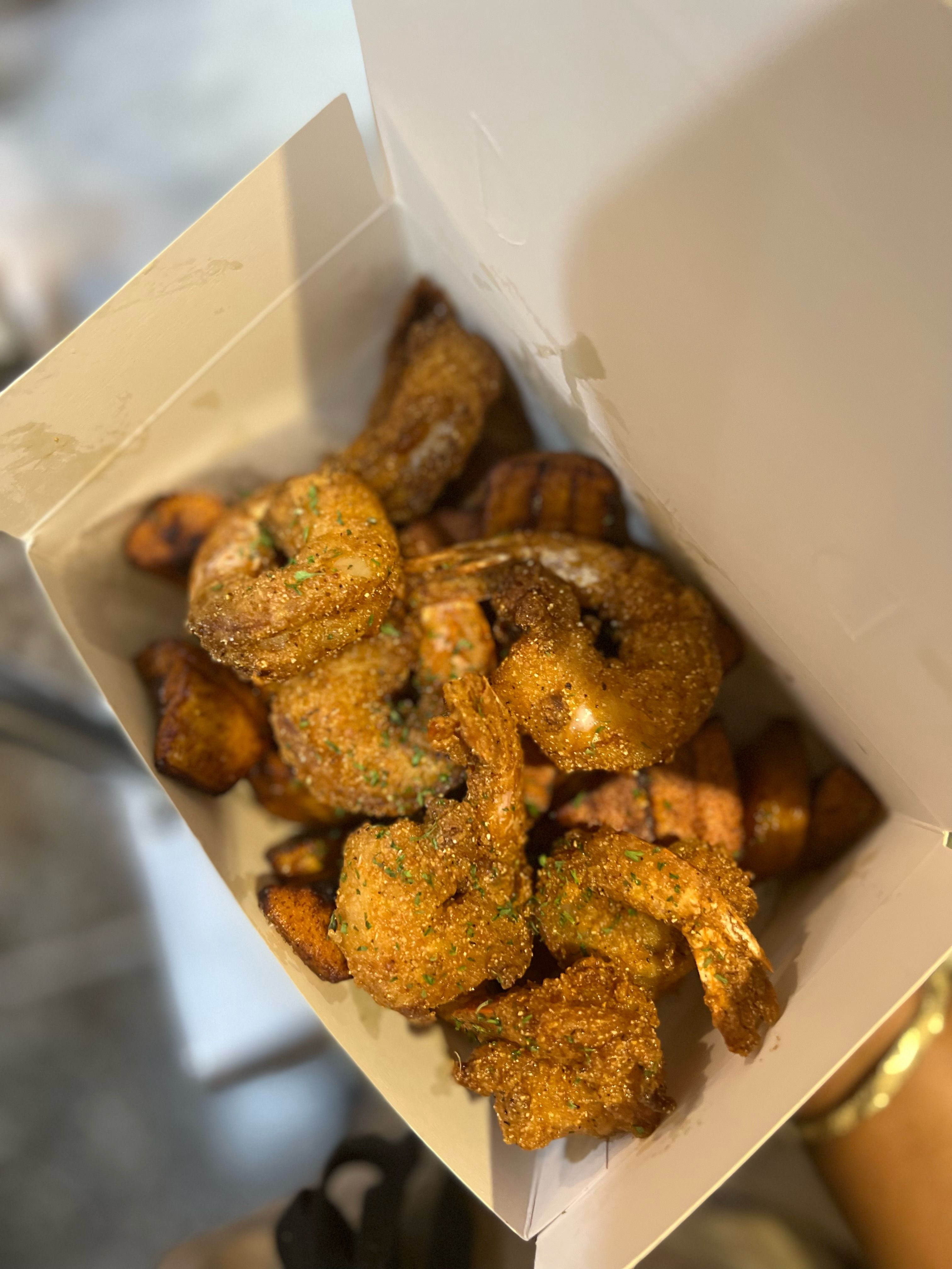 A takeout box filled with crispy fried shrimp and sweet Caribbean plantains from Jus Fishy & Beyond.