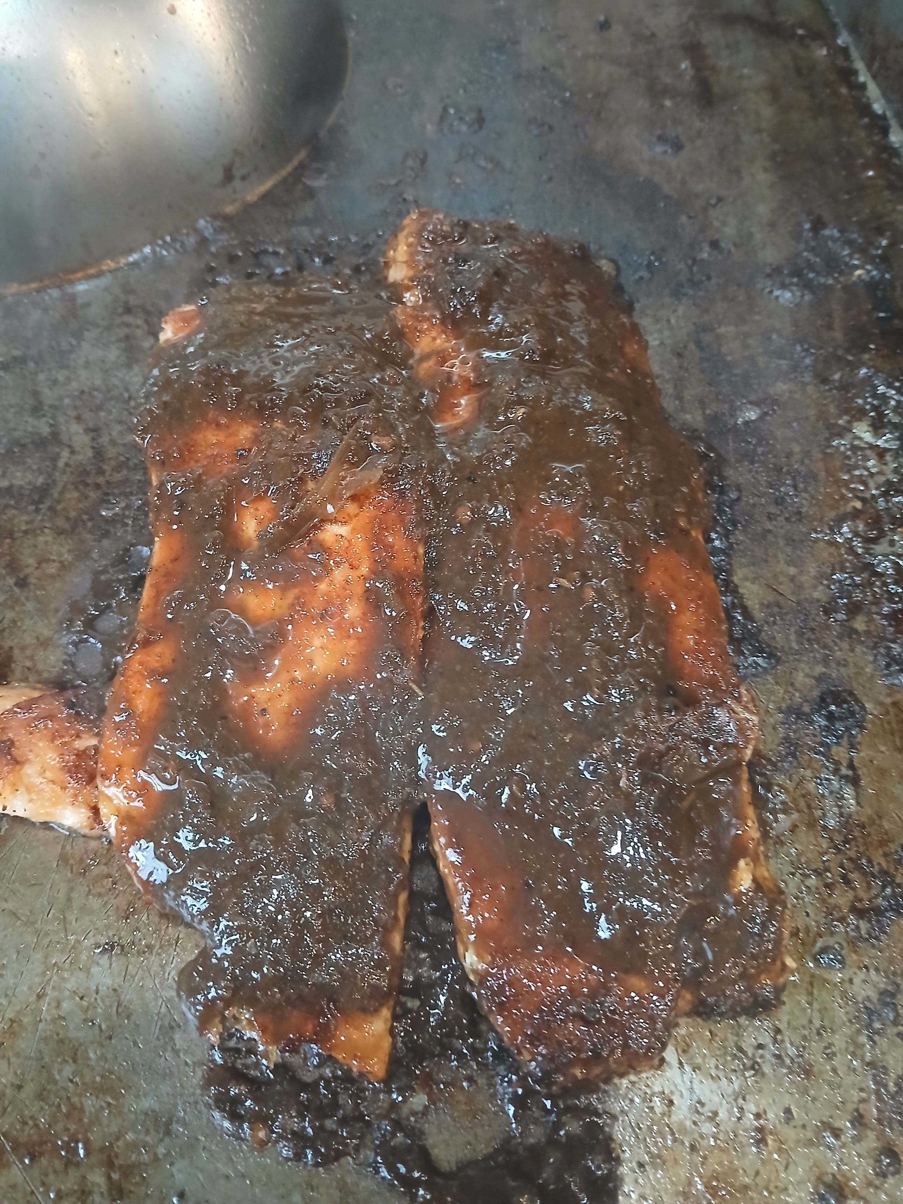 Two fresh salmon fillets grilling with a thick coating of traditional jerk seasoning, showcasing our transparent and ethical cooking process on Flatbush Ave.