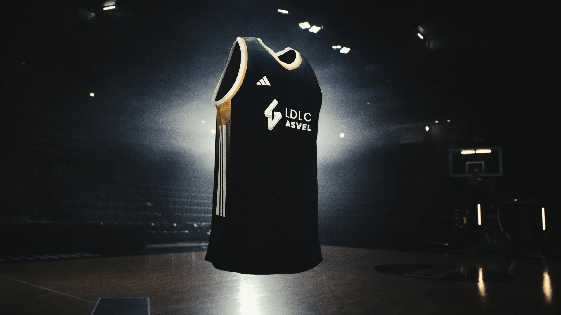 Un maillot noir LDLC ASVEL suspendu dans une salle de basket sombre.