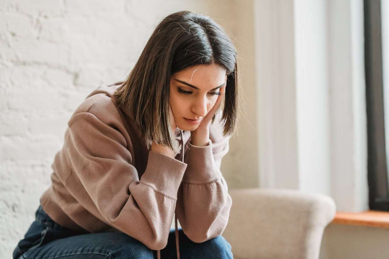 Sad woman sitting on the couch thinking how to get over a crush