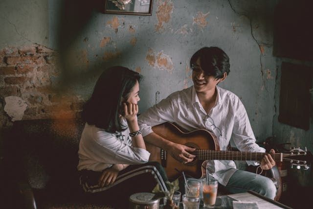 Man playing guitar with girl - first date ideaSource Pexels | Photo by Mẫnn Quang