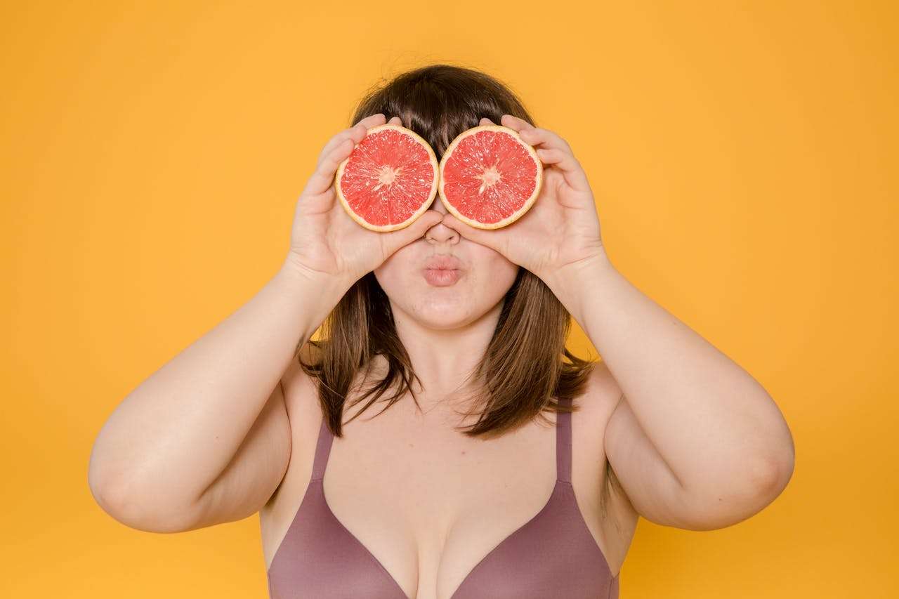 women, model, no face, orange background, grapefruit on eyes