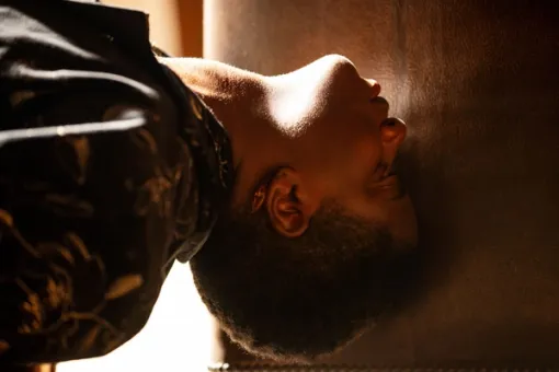 Close-up view of a performer's head seen in profile against a leather chair