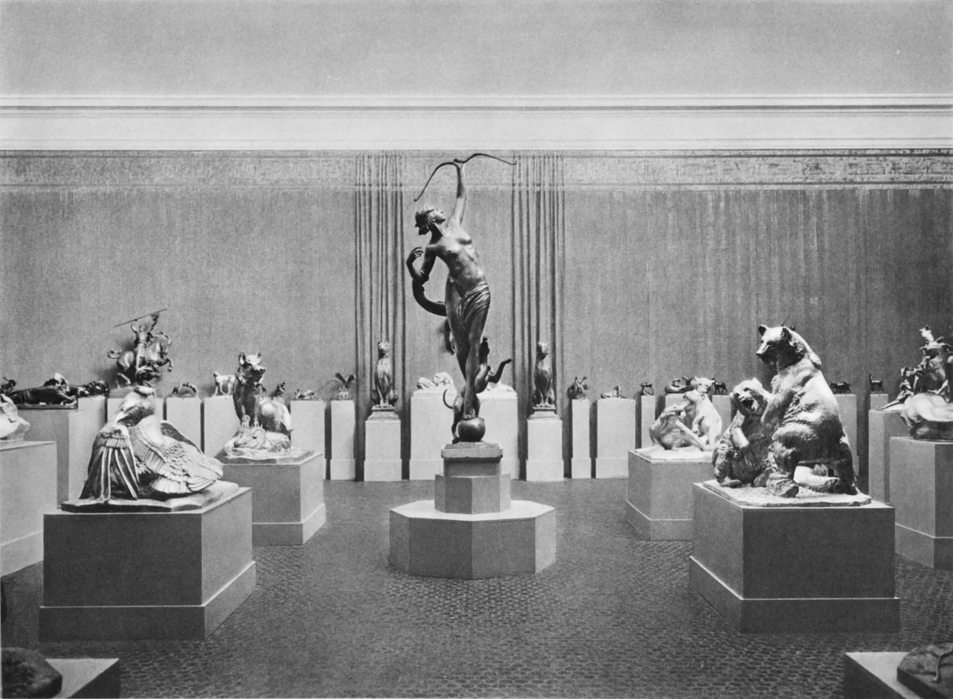 Photograph of sculptures on pedastals in a gallery whose walls are lined with a curtain