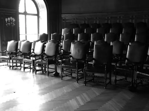 A black and white photograph of a room containing neat rows of chairs.