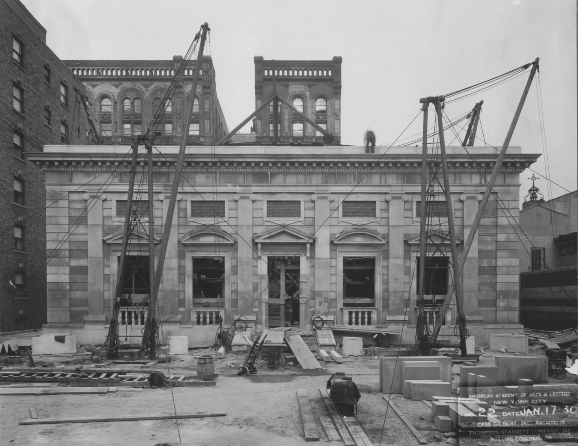 A black and white photograph of Arts and Letters's neoclassical building with cranes and other building materials visible in the foreground.