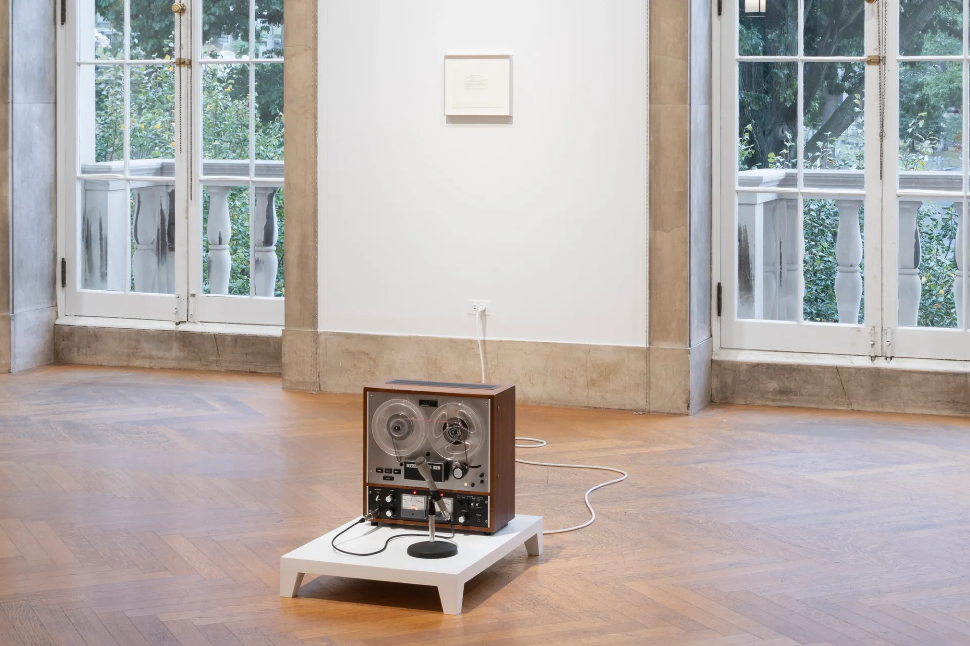 A reel-to-reel tape recorder sits on a wooden plinth