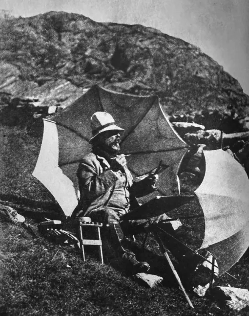 A black and white photograph of a man painting on a hillside.