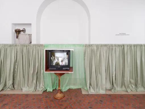 Television sculpture in front of a curtain.