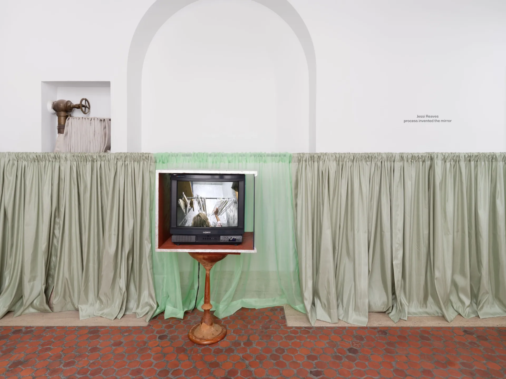 Television sculpture in front of a curtain.