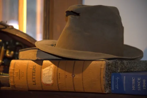 A well-worn man’s Trilby hat sits atop a large book.