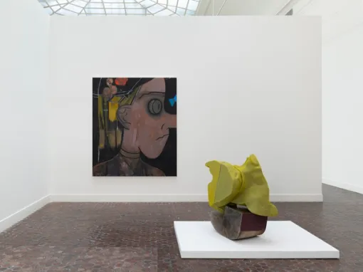 A large painting displaying a girl in profile with a cartoonish expression hangs on the wall. In the foreground, a sculpture with a lime green bulbous form resting atop another curvaceous form sits on a white horizontal base.