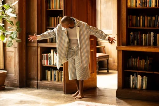 A performer moves with arms outstretched through a wood-paneled library